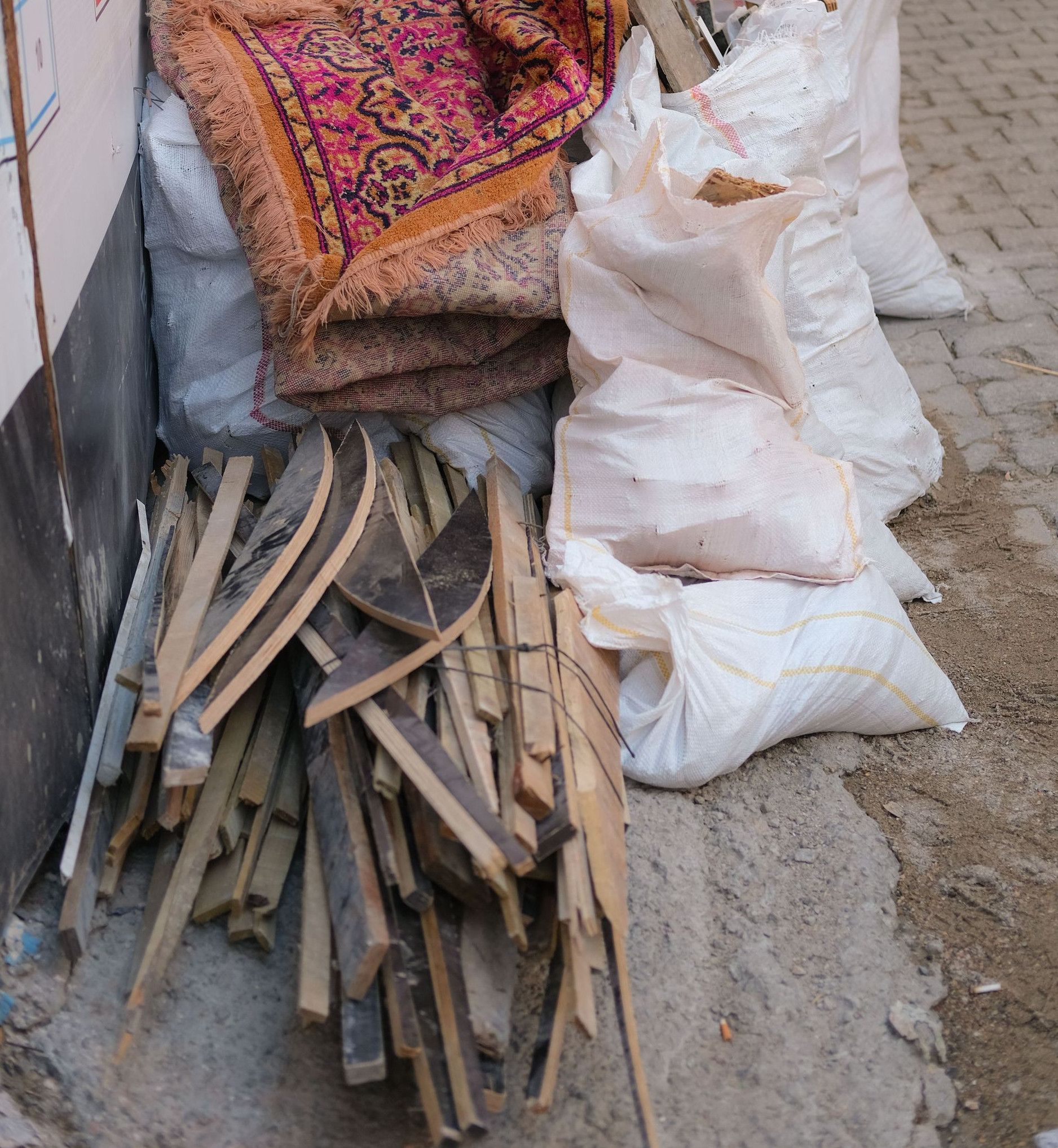 Discarded construction materials on a city street, including wood planks and sacks.