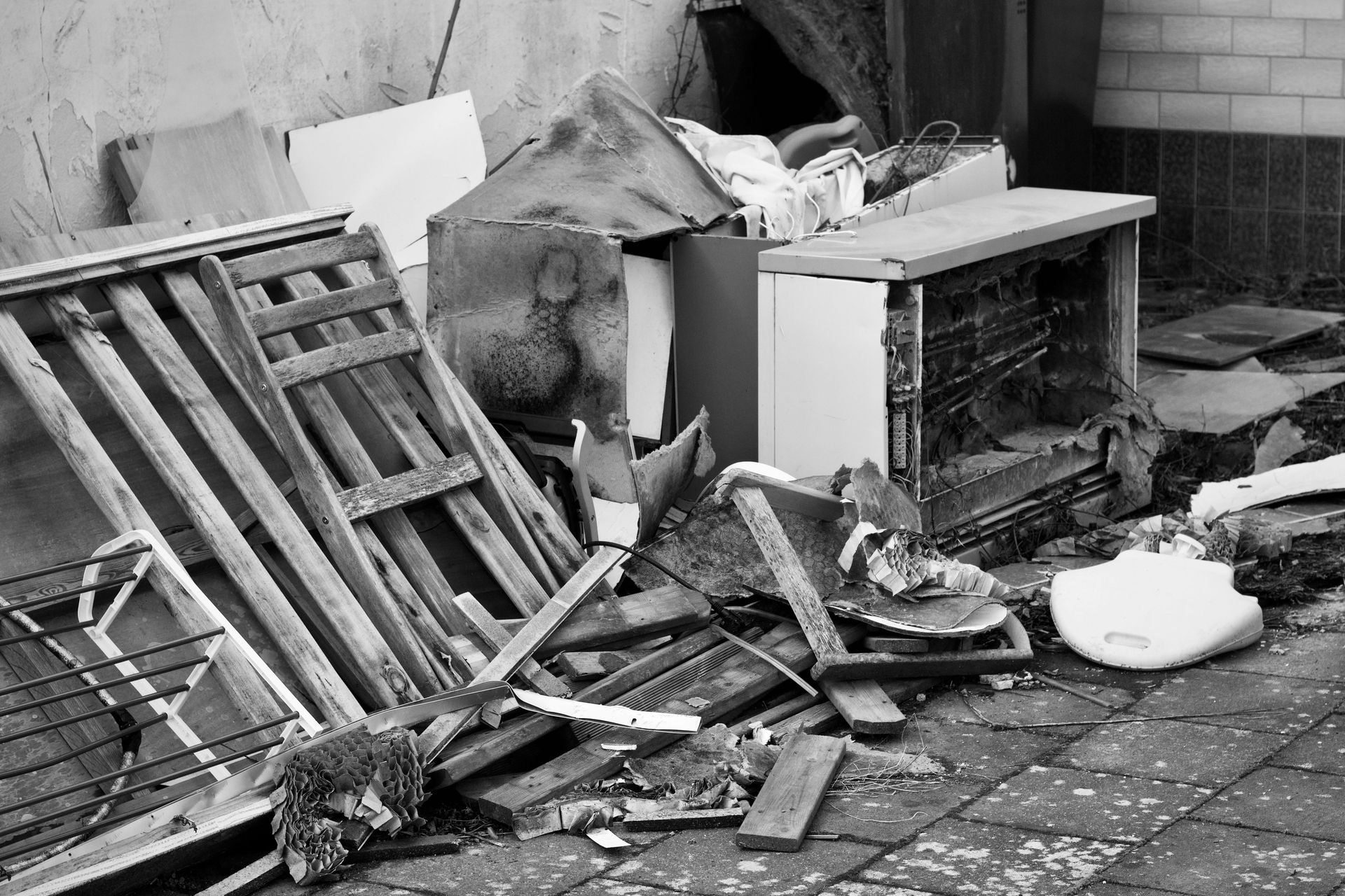 Black and white image of a pile of discarded objects in an urban setting, highlighting decay.